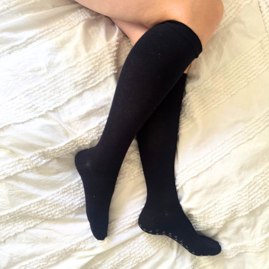 pregnant women wearing navy compression  knee-high socks on a white textured surface